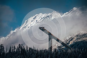 Silueta skokanského mostíka, zimné biele zasnežené hory v pozadí. Vysoké Tatry, Slovensko