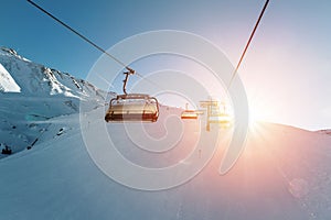 Ski lift empty ropeway on hilghland alpine mountain winter resort on bright sunny evening . Ski chairlift cable way with people