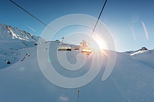 Ski lift empty ropeway on hilghland alpine mountain winter resort on bright sunny evening . Ski chairlift cable way with