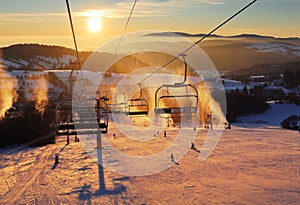 Ski lift empty ropeway on hilghland alpine mountain winter resort on bright sunny evening . Ski chairlift cable way with people