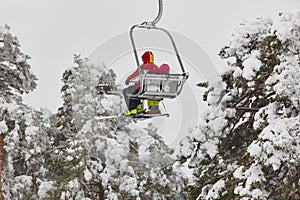 Ski lift with people on a snow forest landscape. Winter