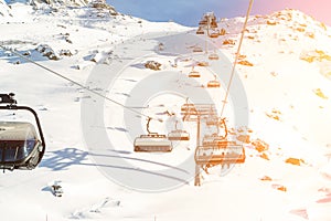 Ski lift ropeway on hilghland alpine mountain winter resort on bright sunny day. Ski chairlift cable way with people