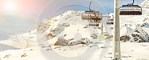 Ski lift ropeway on hilghland alpine mountain winter resort on bright sunny day. Ski chairlift cable way with people