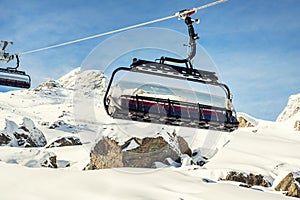 Ski lift ropeway on hilghland alpine mountain winter resort on bright sunny day. Ski chairlift cable way with people