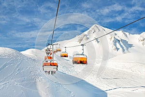 Ski lift ropeway on hilghland alpine mountain winter resort on bright sunny day. Ski chairlift cable way with people