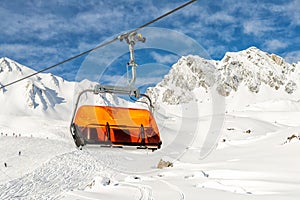 Ski lift ropeway on hilghland alpine mountain winter resort on bright sunny day. Ski chairlift cable way with people enjoy skiing