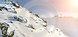 Ski lift ropeway station on hilghland alpine peak at mountain winter resort on bright sunny day. chairlift cable with