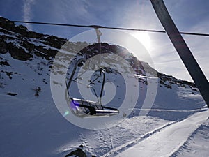 Ski lift sit above ski empty slope in italian Dolomites in winter sunny blue sky day