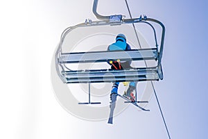 Ski lift on the slop in mountain ski resort with skier on the lift. Cableway for tourists, skiers and snowboarders