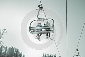 Ski lift on the slop in mountain ski resort with skiers on the lift. Cableway for tourists, skiers and snowboarders