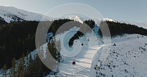 Ski lifts moving up and down over slope trail in beautiful winter landscape mountains resort, sun rising on clear day.