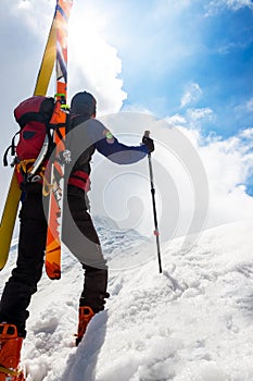 Ski mountaineer walking up along a steep snowy ridge with the s