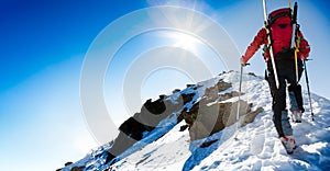 Ski mountaineer walking up along a steep snowy ridge with the sk photo