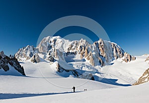 Ski mountaineers ascend the Vallee Blanche glacier. In background the est face of Mont Blanc, Chamonix
