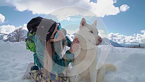 Ski resort entertainments. Friends have fun on the ski resort. Young girl with blonde hair caress Siberian husky