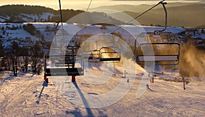 Ski resort, skiers on the ski lift, white snow pine trees at pink sunset or dawn, Krahule Slovakia