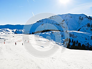 Ski run on snow slopes of mountains in sunny day