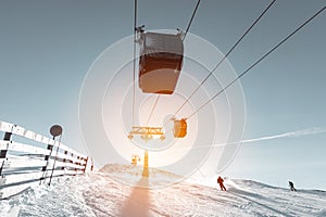 Ski slope with skier and cable car pylon in sun backlight