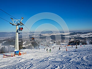 Ski slope with skiers, snowboarders and chairlift