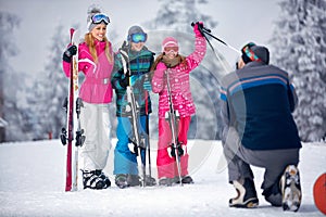 Ski, snow sun and fun - father taking picture of family on snow