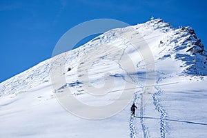 Ski tourer snow shoe hiker climbing the mountain, blue sky sunny