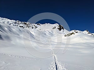 Ski tourers make a lonely track through the deep snow in the mountains above Davos. Ski mountaineering in the Swiss Alps