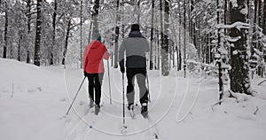 Ski touring in deep fresh snow - young couple skiing in snowy winter forest