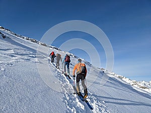 Ski touring group on the way to the summit. Mountaineering with skis in winter on the Gemsfairenstock in Uri. Swiss Alps