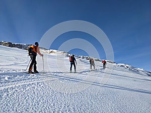 Ski touring group on the way to the summit. Mountaineering with skis in winter on the Gemsfairenstock in Uri. Swiss Alps