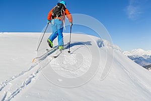 Ski touring man reaching the top at sunny day.