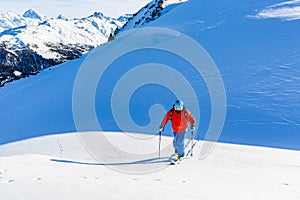 Ski touring man reaching the top at sunny day.