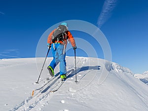 Ski touring man reaching the top at sunrise.