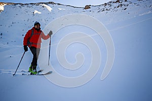 Ski touring man reaching the top at sunrise.