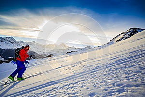 Ski touring man reaching the top at sunrise.