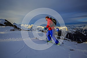 Ski touring man reaching the top at sunrise.