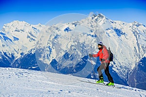 Ski touring man reaching the top in Swiss Alps.