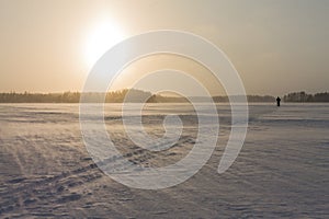 Ski track being covered by falling snow at a frozen lake.