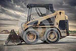 skid steer loader with dark clouds in the background photo