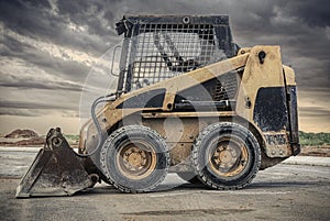 skid steer loader with dark clouds in the background