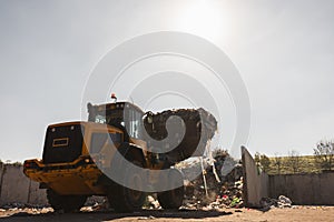 Skid steer loader moving waste material, shaking out a scrap grapple