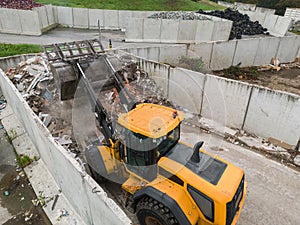 Skid steer loader moving waste material, shaking out a scrap grapple