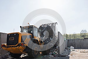 Skid steer loader moving waste material, shaking out a scrap grapple