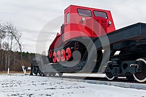 Skidder on a railway flatcar against the background of a forest in winter