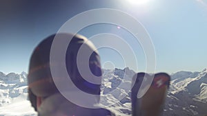 Skier from behind with epic view on snowy mountains in background. Sun flare in lens.