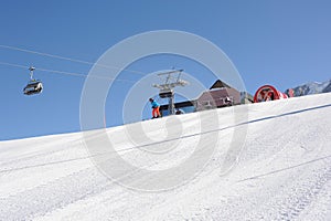 Skier in blue jacket, black helmet and orange pants on the piste slope in winter with snow mountains in Alps