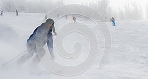 A skier carves down the slope during a snowy day.