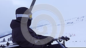 Skier on the chairlift that transports you to the top of the mountain on a day with fog and blizzard, Grandvalira