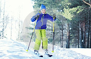 Skier child wearing a sportswear is skiing in winter forest