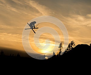 Skier doing a grab off jump in the sunset