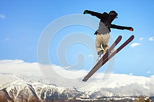 Skier doing high jump above the mountain